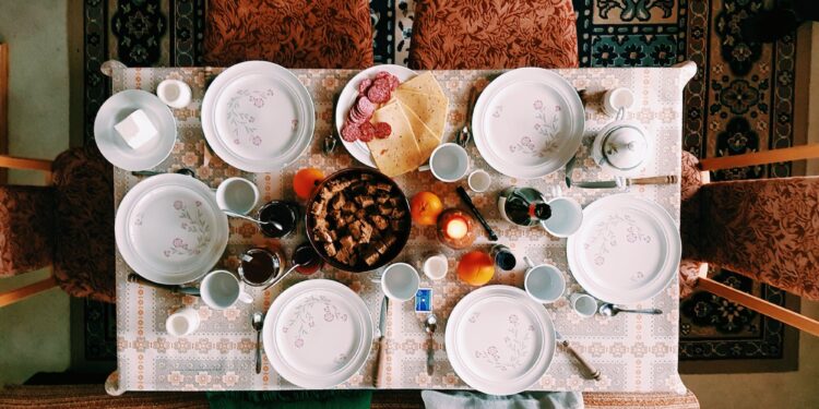 Mooi gedecoreerde tafel met eten in het midden en witte borden